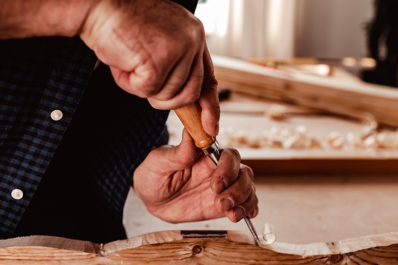 Hands of a carpenter working with chisel and hammer