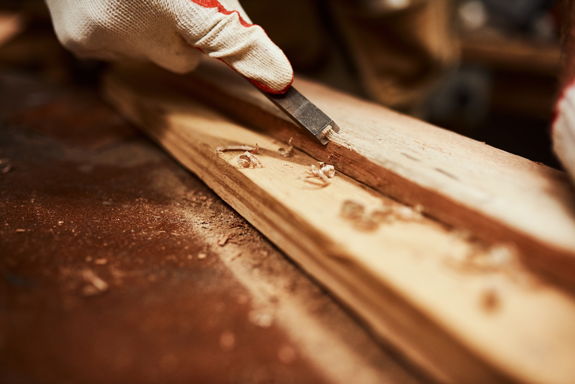 This tool works wonders. Closeup of an unrecognizable carpenter filing down a piece of wood inside of a workshop at night.